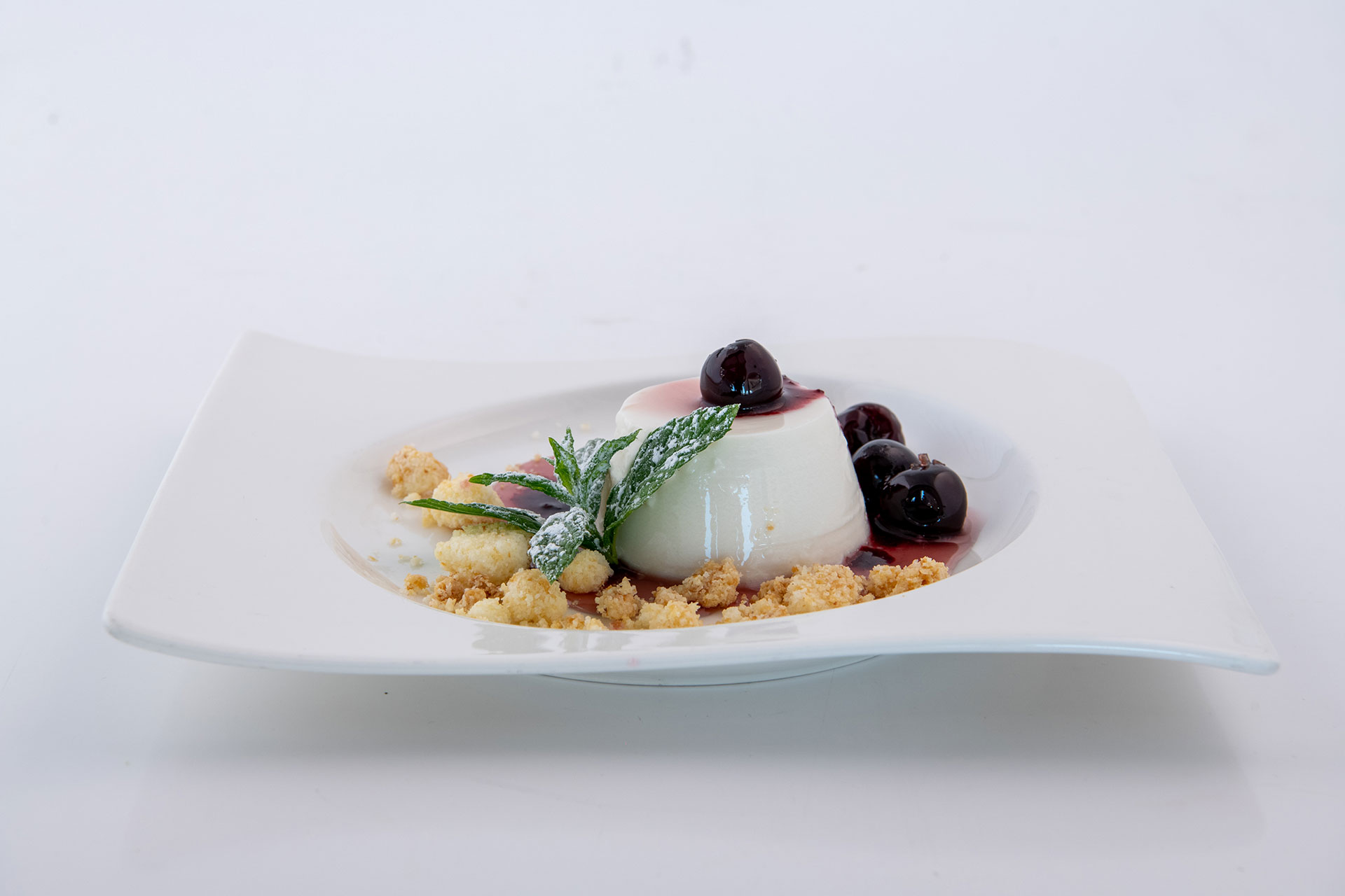 Elounda Beach Hotel Argonaut Restaurant ALMOND MILK PANNACOTTA FLAVORED WITH ROSE, SYRUP SOUR CHERRIES AND COCONUT CRUMBLE